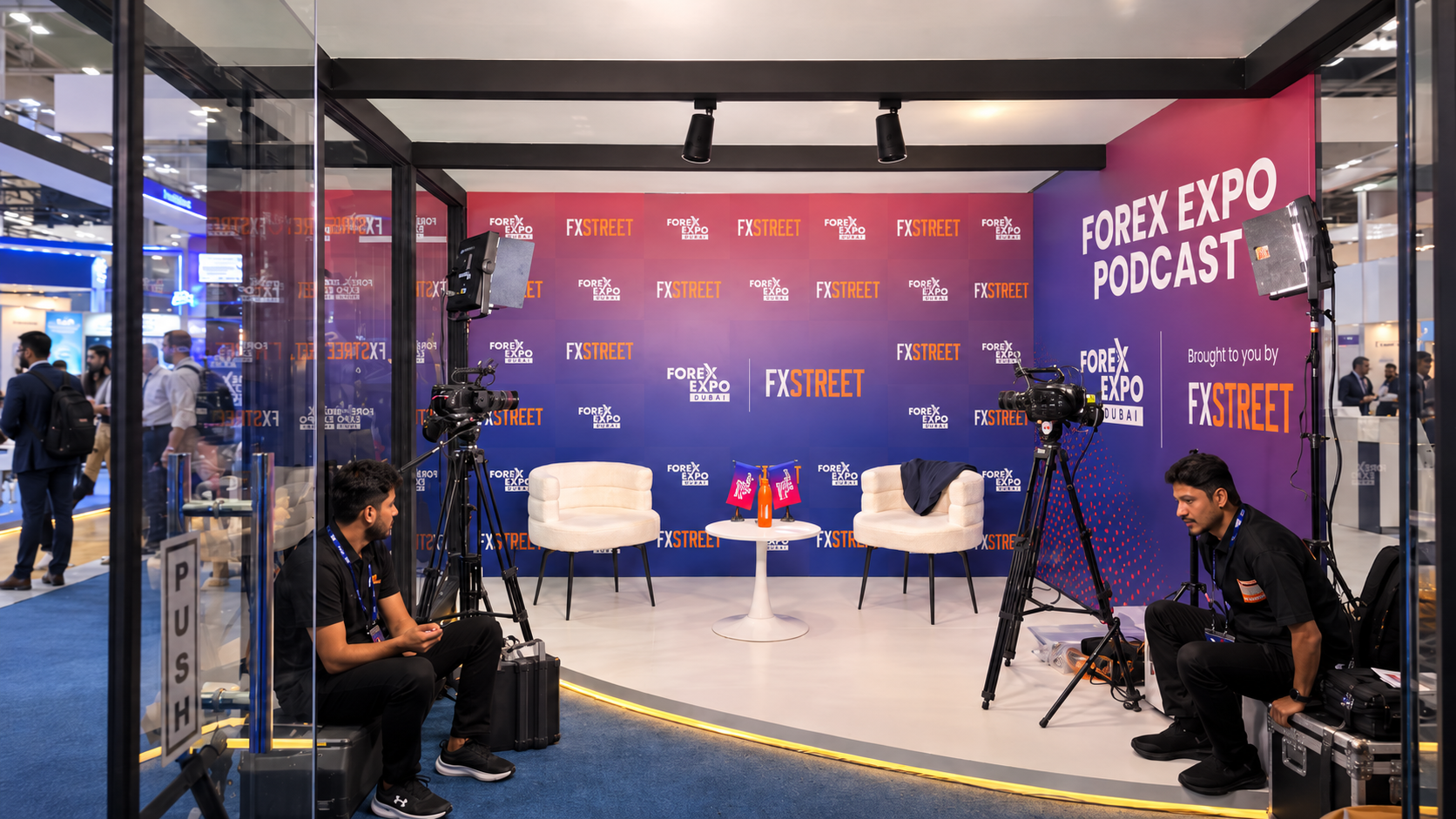 Header 1 | LeapRate | LeapRate Podcast interview set at a Forex Expo booth: two white chairs, a small round table, branded backdrop, and cameras filming.
